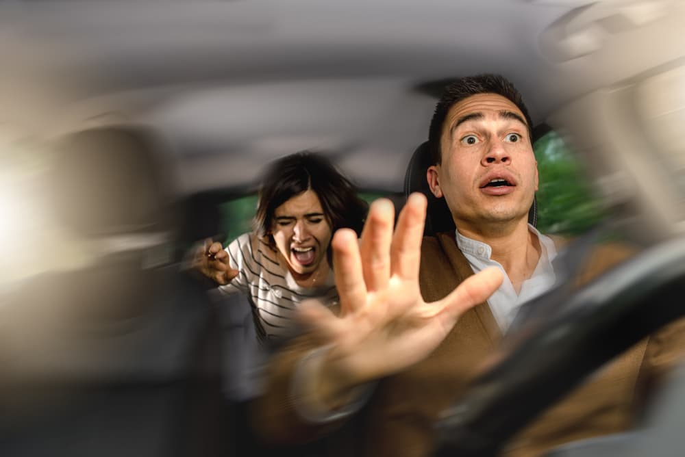 Frightened couple in car experiencing a collision, screaming in fear during the accident.
