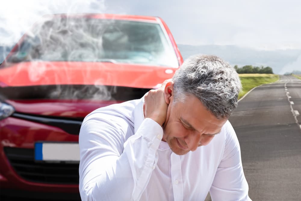 Mature man experiencing neck pain near broken-down vehicle.