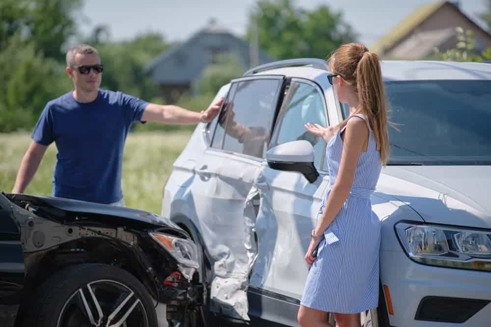 Two drivers in heated discussion over fault in car accident. Concept of road safety and insurance claims.