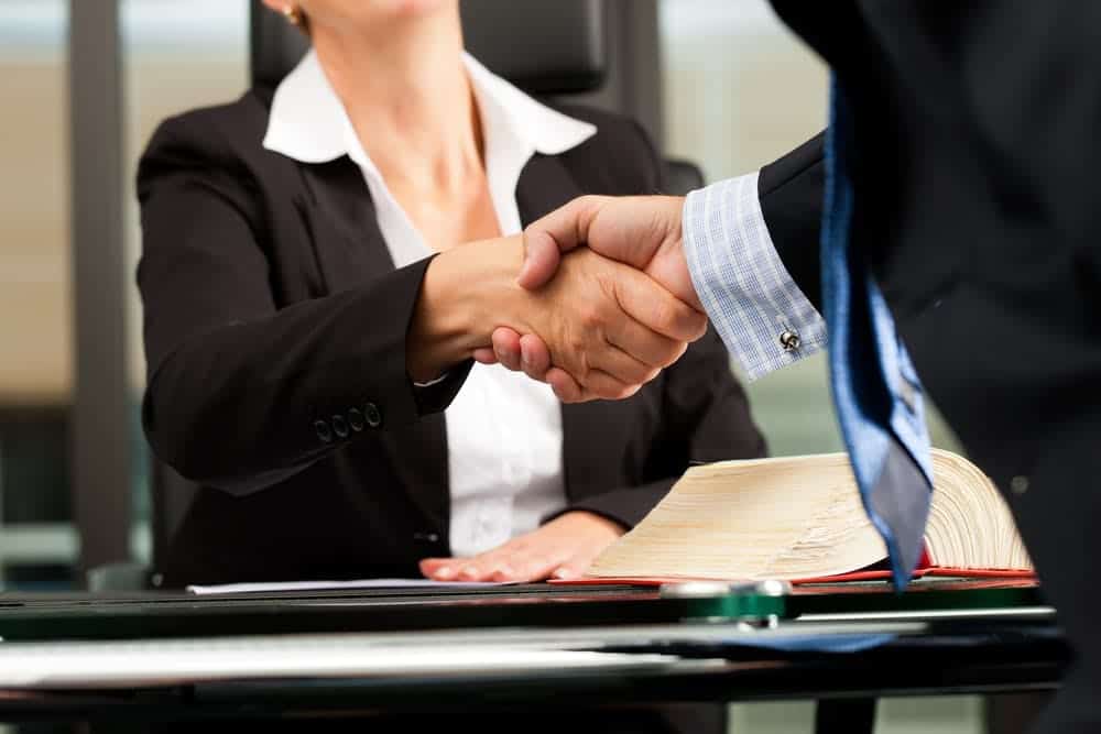 Professional woman lawyer or notary shaking hands with client in her office.