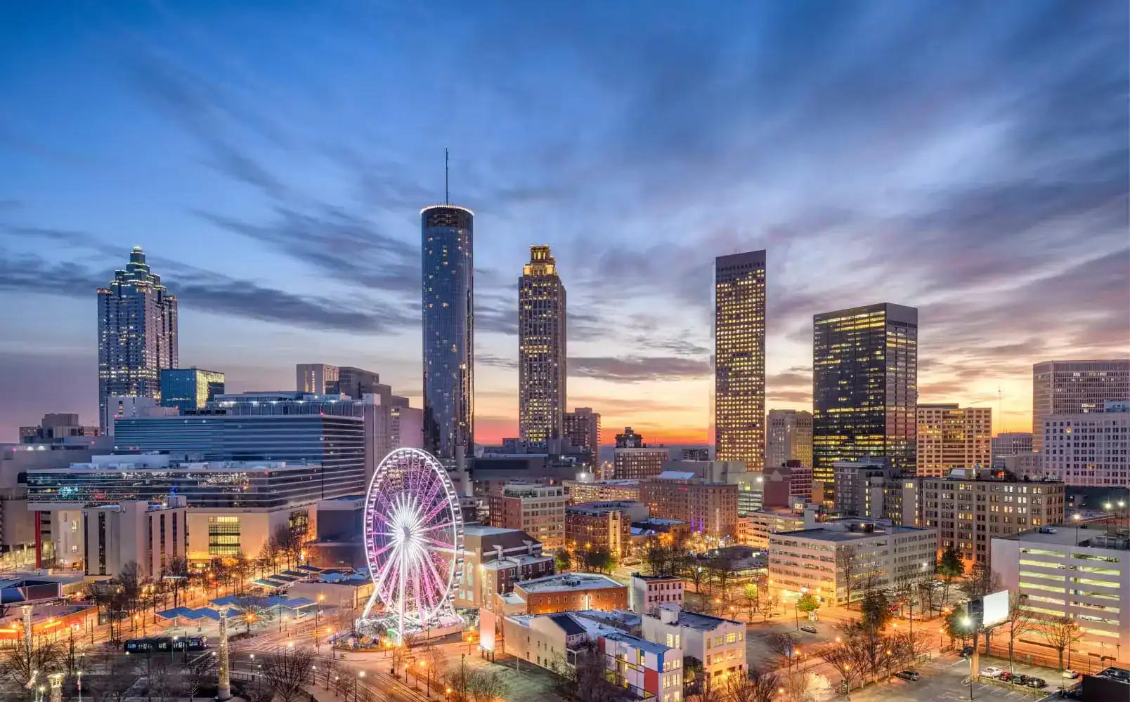 Beautiful Atlanta downtown skyline at sunset with tall buildings and illuminated SkyView Ferris wheel.