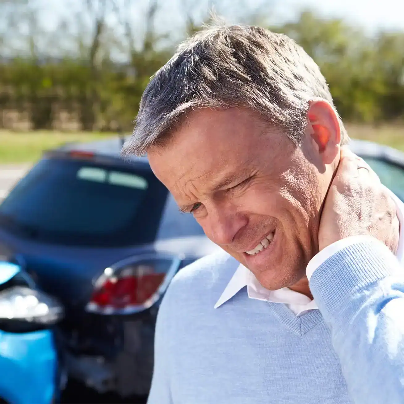 Middle aged man holding neck in pain after car accident injury