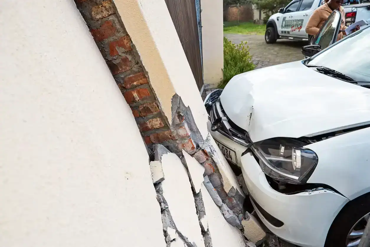 White car crashed into a building wall causing visible structural damage
