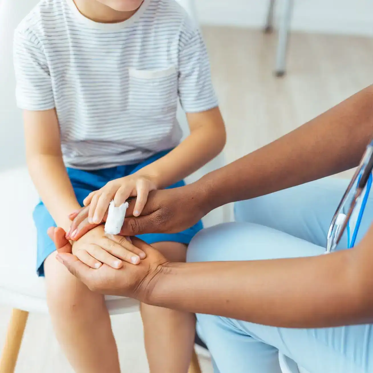 Doctor treating young child’s hand injury in medical clinic after accident
