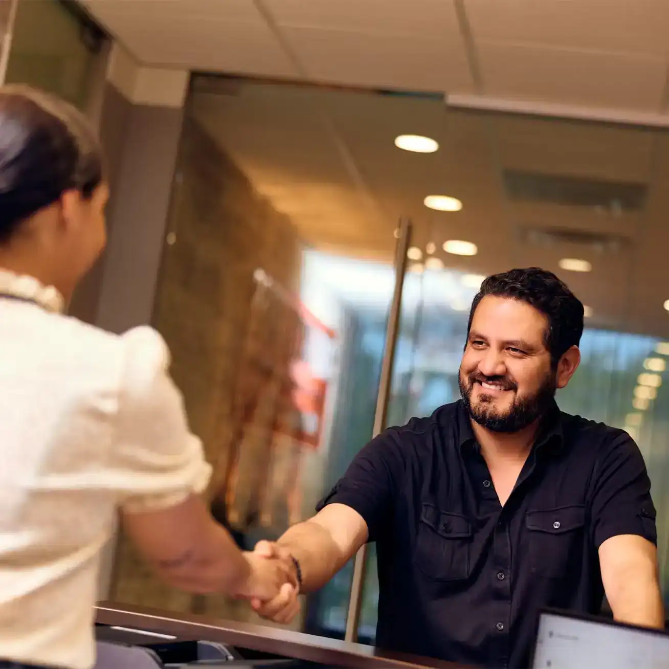 Smiling client shaking hands with personal injury lawyer at law office consultation