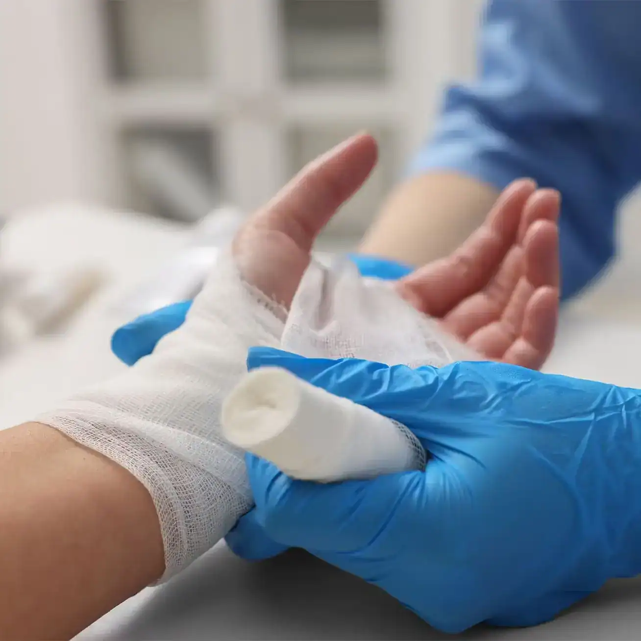 Medical professional bandaging patient’s hand injury with gauze