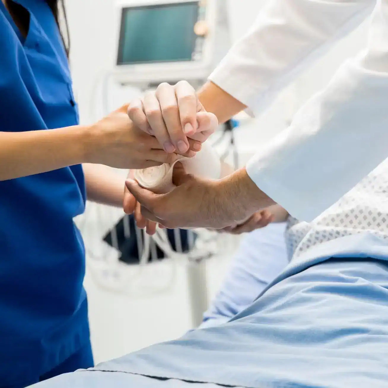 Doctors and nurses treating injured patient’s arm in hospital after personal injury accident.