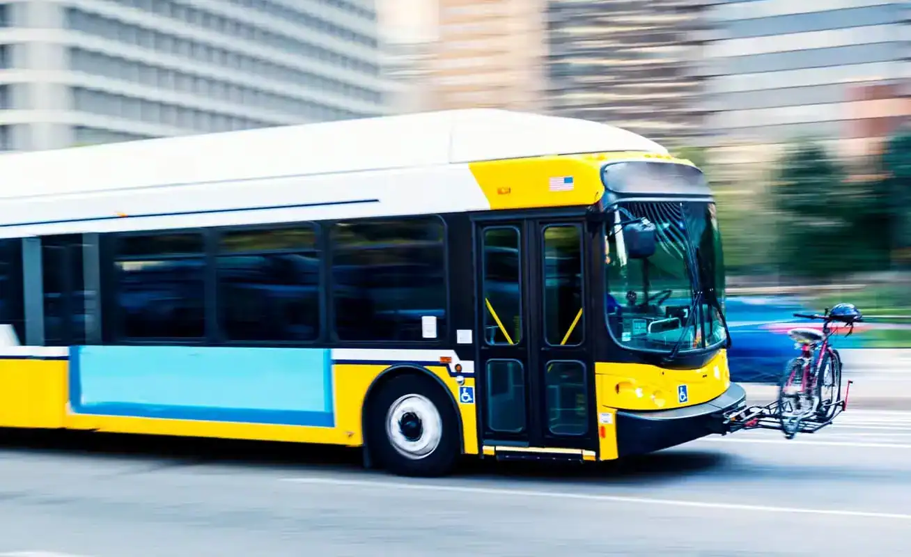 Yellow city bus driving in downtown Houston, representing bus accident and public transportation injury claims