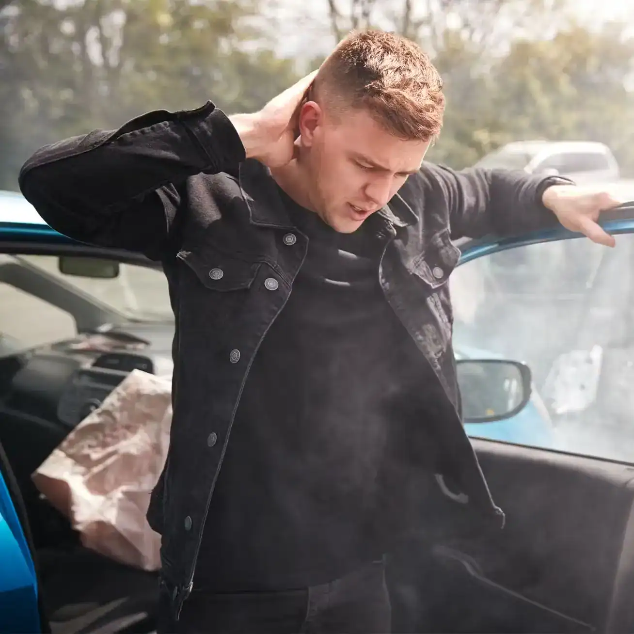 Young man holding neck in pain after car accident with airbag deployed