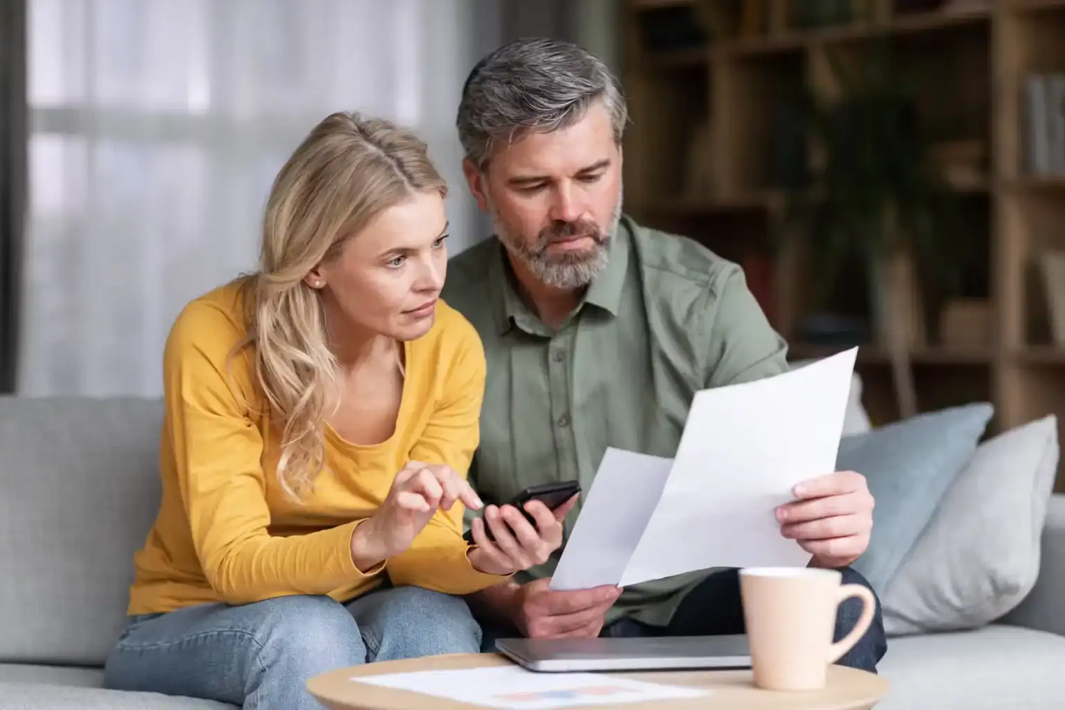 Concerned couple reviewing legal documents and bills at home after accident