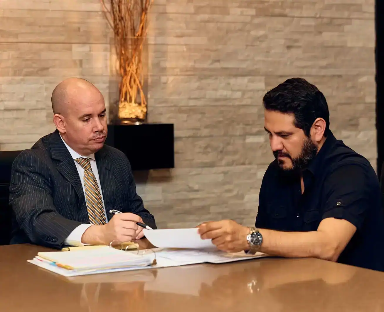 Personal injury lawyer consulting with client and reviewing legal documents during case strategy meeting