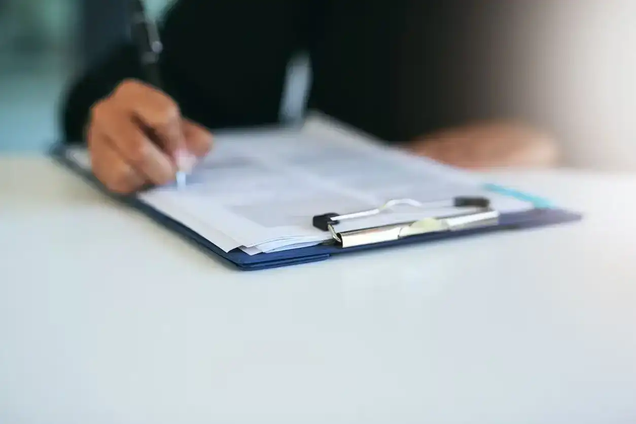 Close-up of person signing legal documents on a clipboard at lawyer’s office