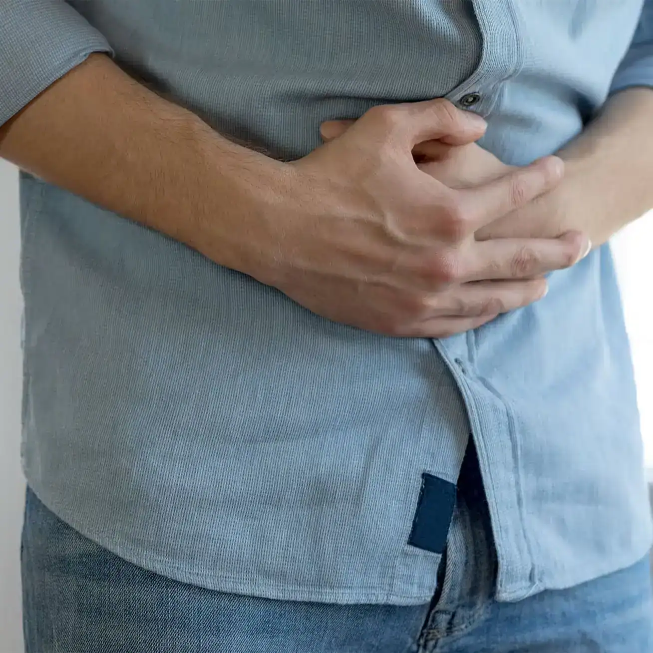 Close-up of man holding stomach in pain, possible injury or internal trauma
