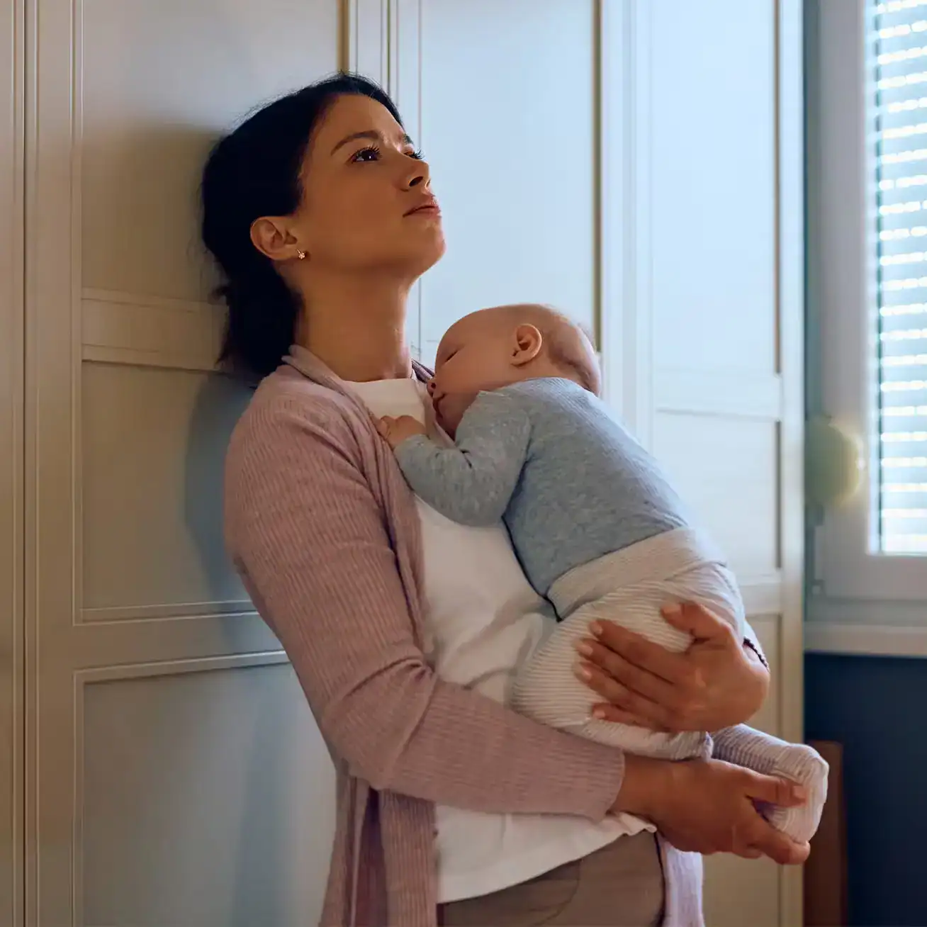 Worried mother holding baby at home representing emotional distress and family struggles after a personal injury