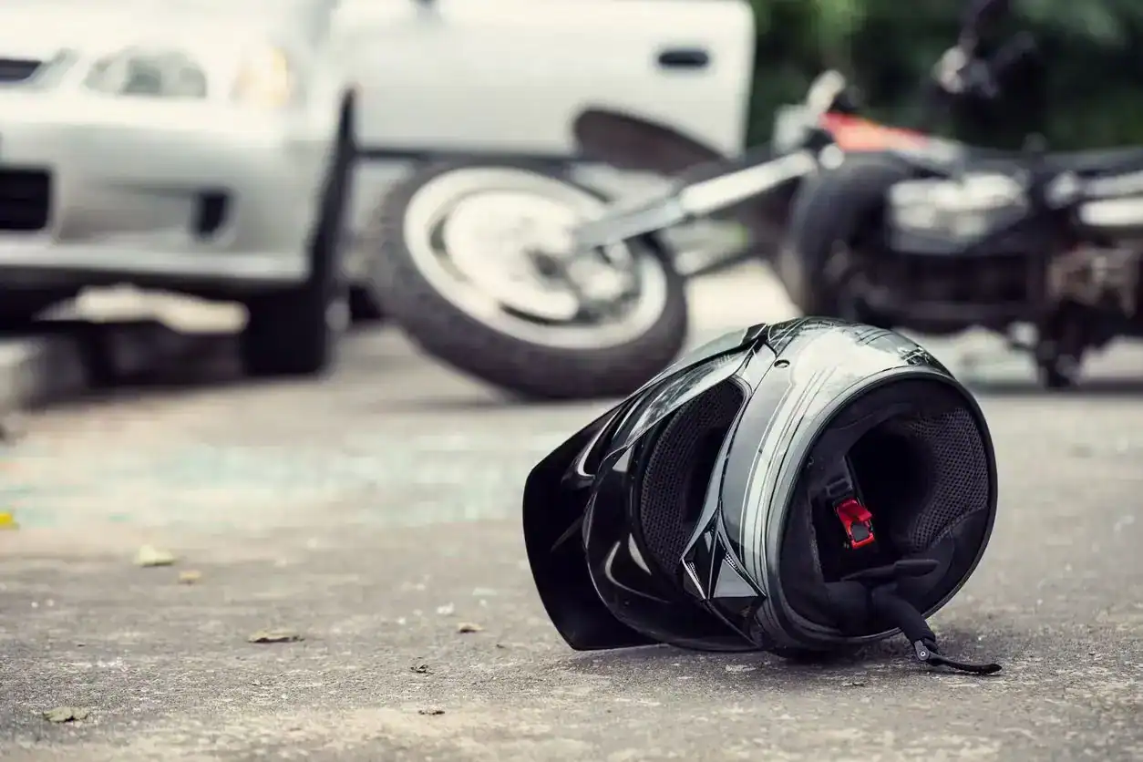 Motorcycle helmet lying on the road after a collision with a car, symbolizing motorcycle accident and injury risk.