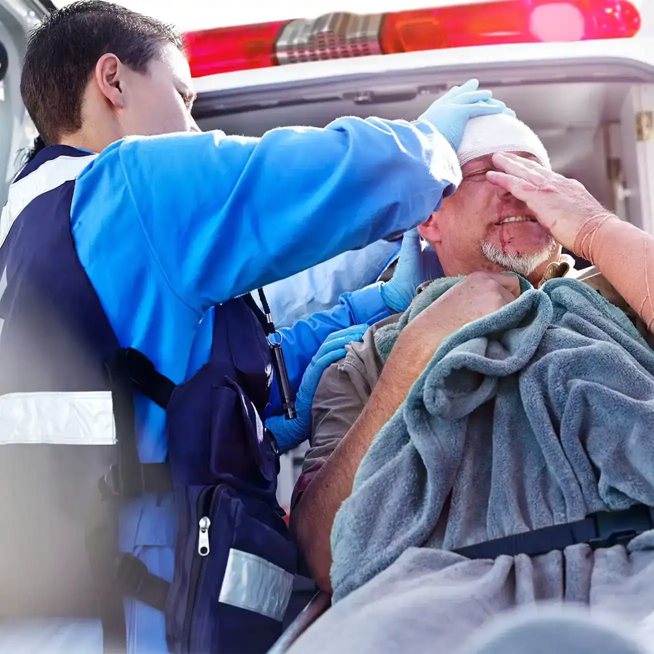Paramedic treating an injured man with a head wound inside an ambulance after an accident.