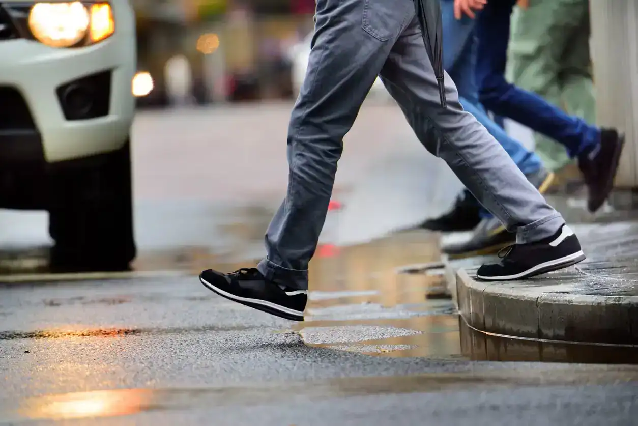 Pedestrian stepping onto crosswalk in front of approaching car highlighting risk of pedestrian accidents