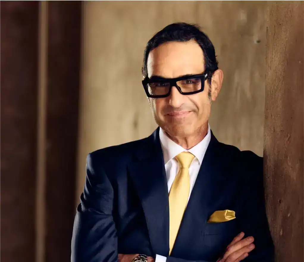 Confident personal injury lawyer in a suit with yellow tie and pocket square posing with arms crossed.