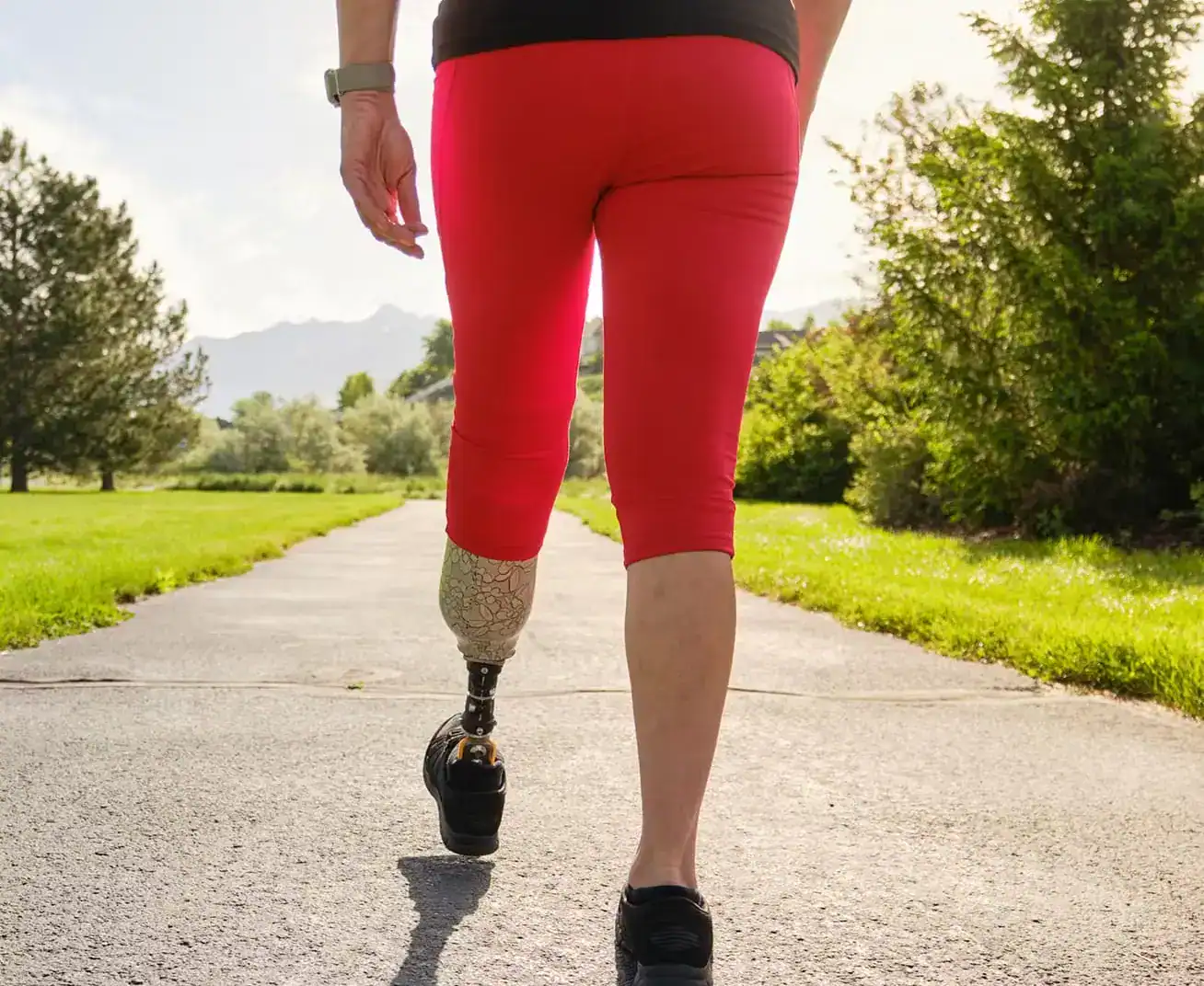Person with prosthetic leg walking on outdoor path during personal injury rehabilitation.