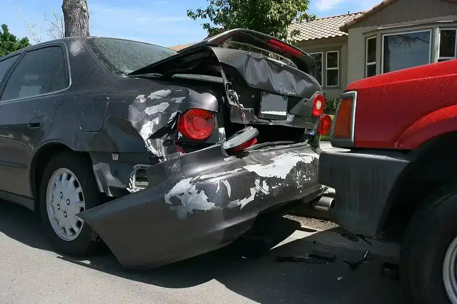 Severe rear-end car accident showing damage to the back of a black sedan after being hit by a red SUV.
