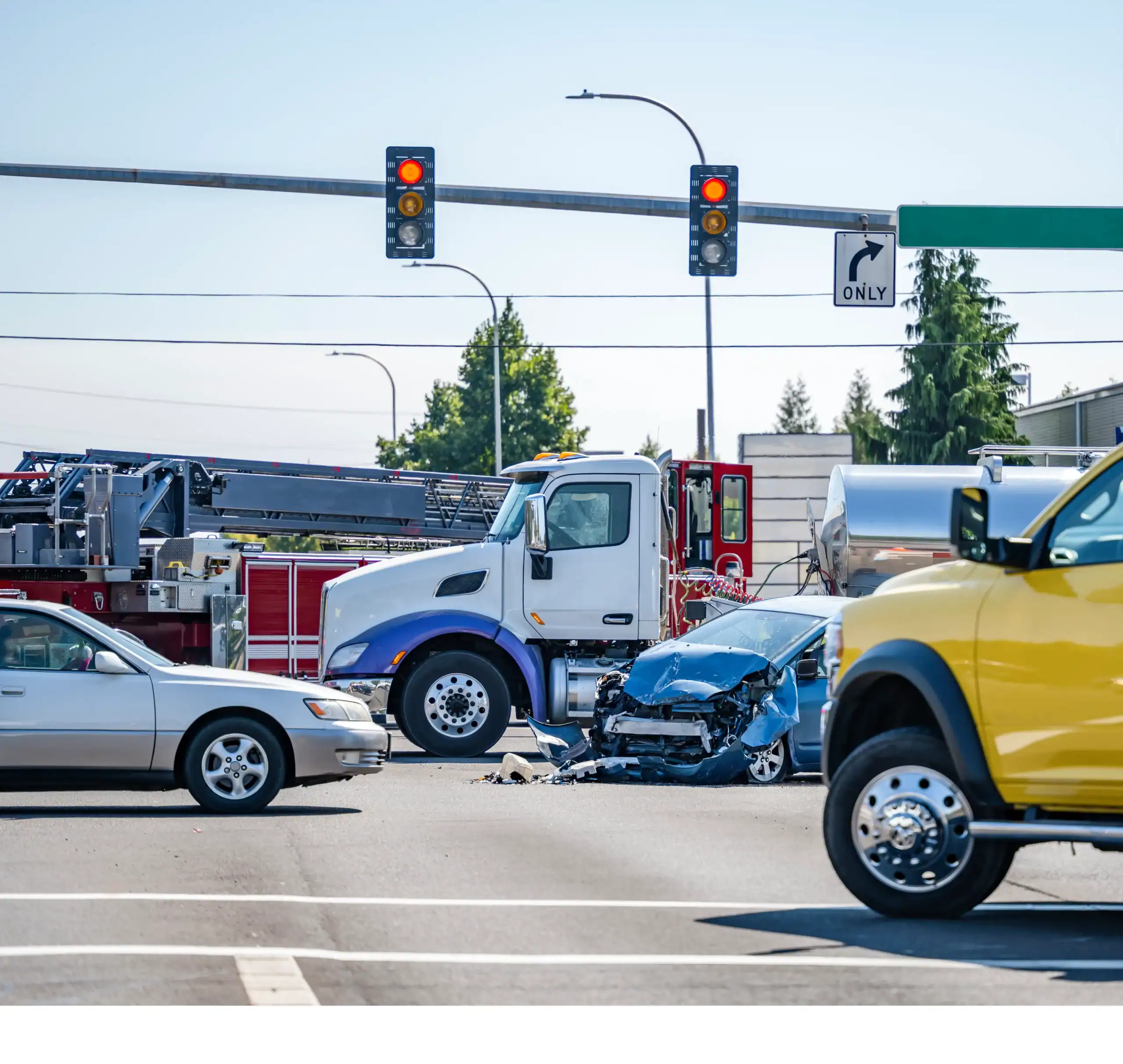 Severe accident between semi-truck and car at busy intersection with traffic lights and emergency vehicles