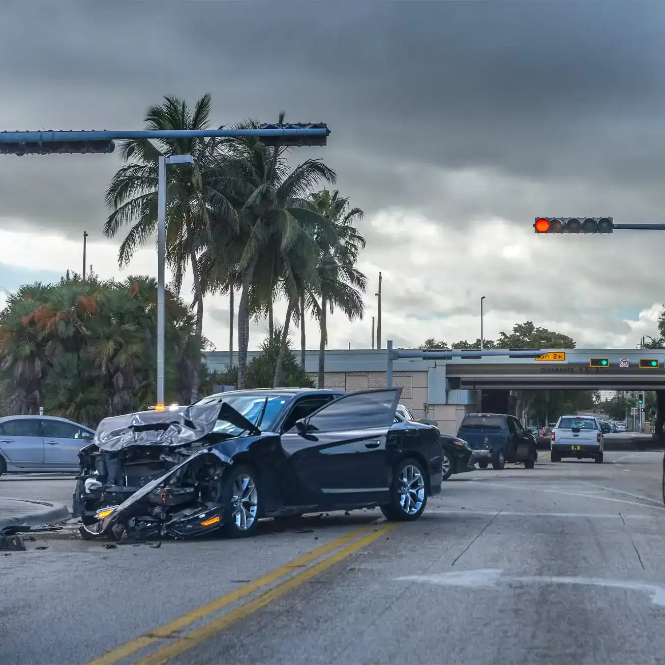 Wrecked black car after a serious accident at an intersection with traffic lights in Miami.