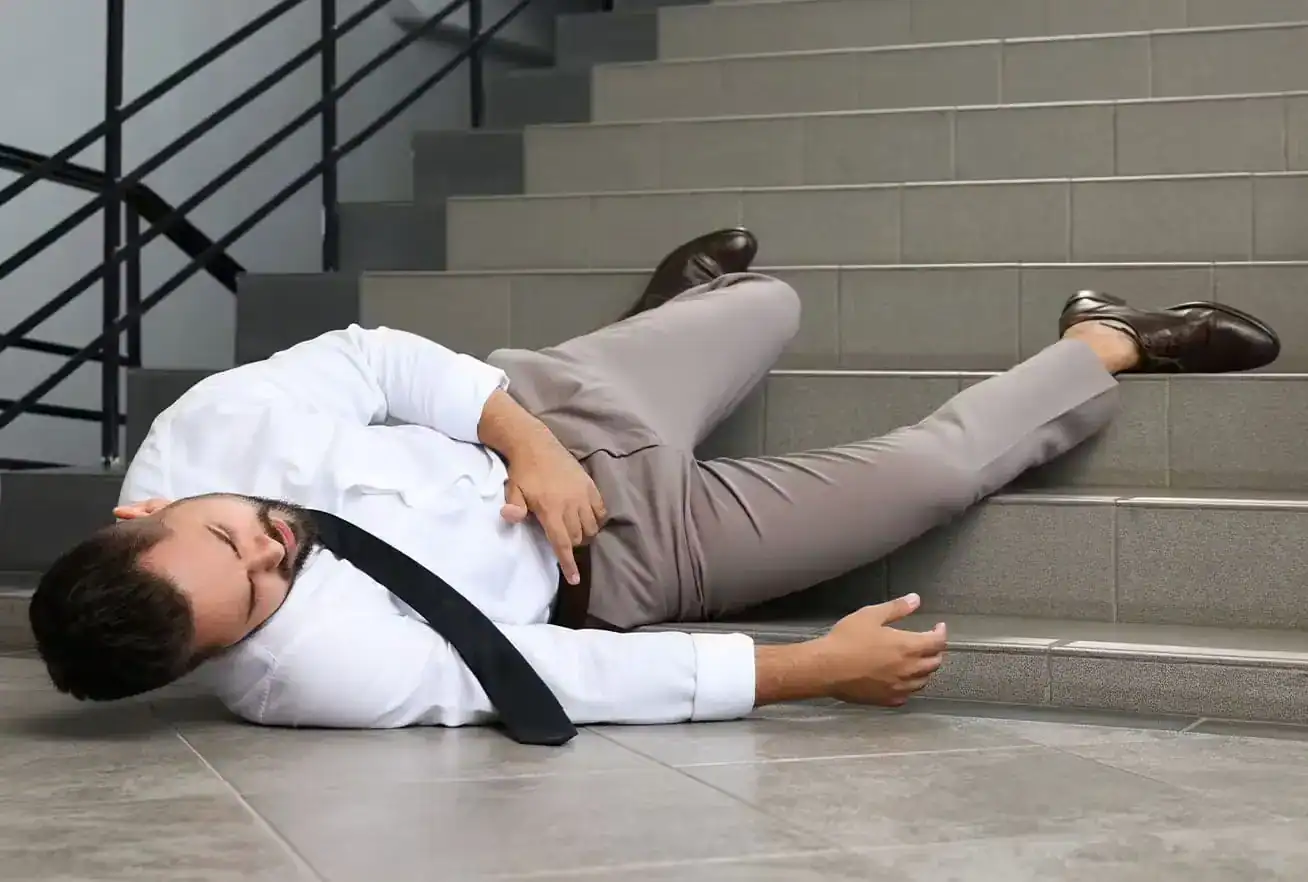 Injured man lying on stairs after slip and fall accident, seeking legal help from a personal injury lawyer.