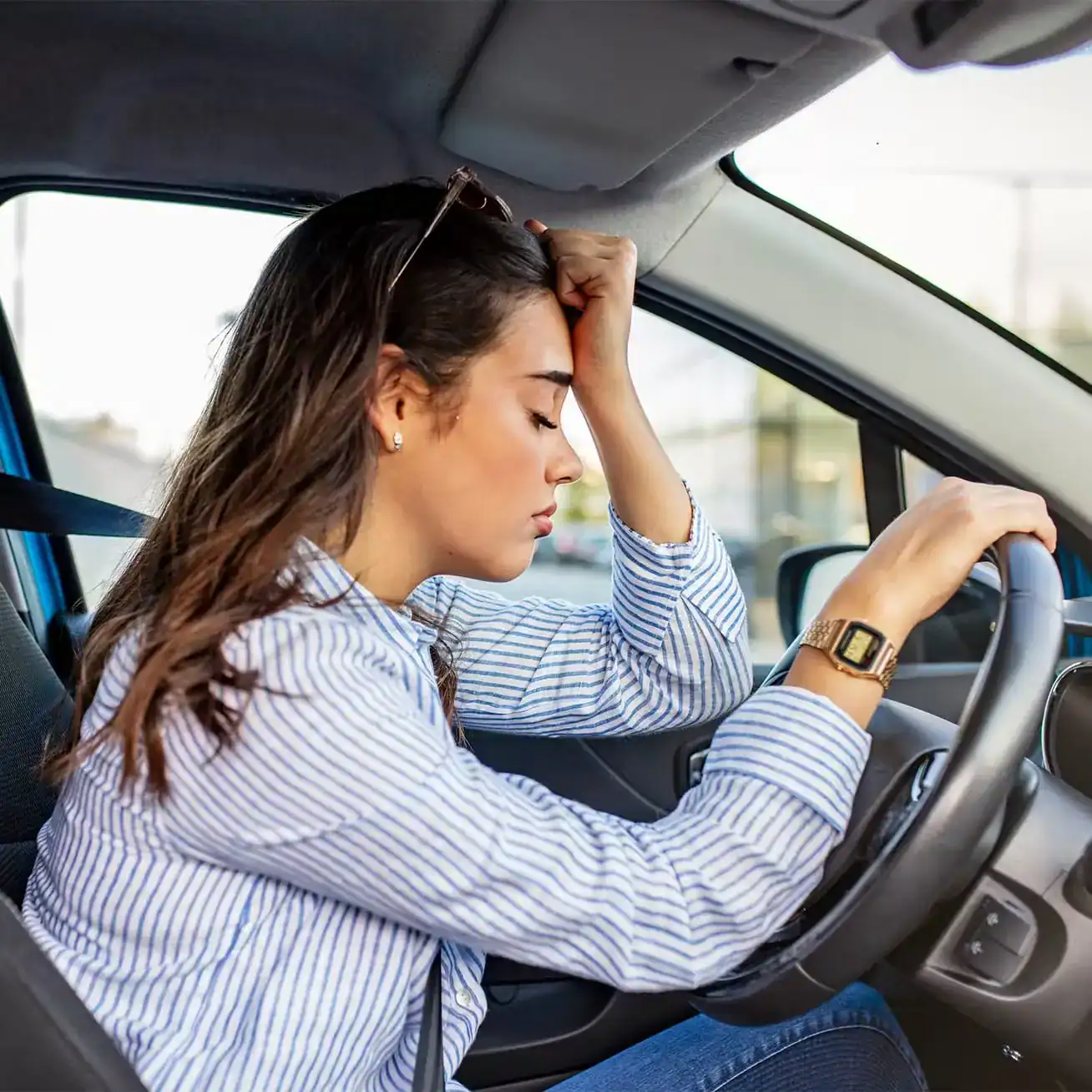 Frustrated young woman driver holding her head in stress while sitting in car