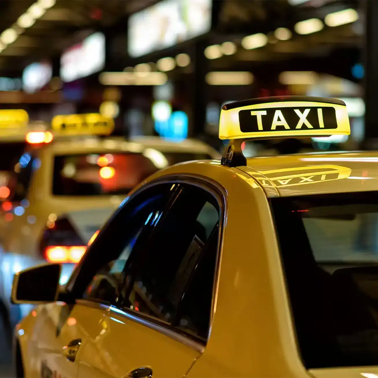 Yellow taxi cab at night with illuminated taxi sign in traffic