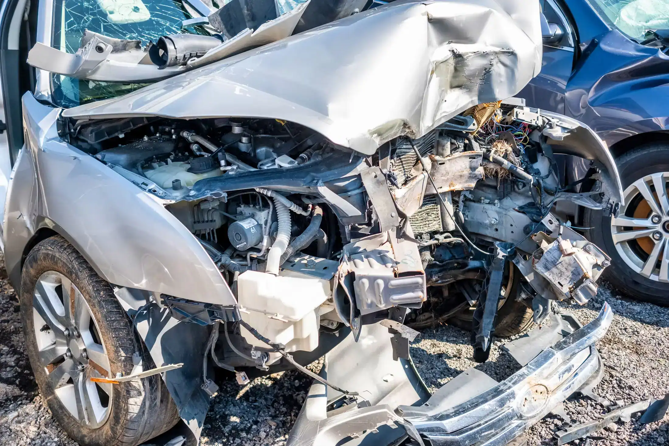 Severely damaged car with crushed front end and exposed engine after accident