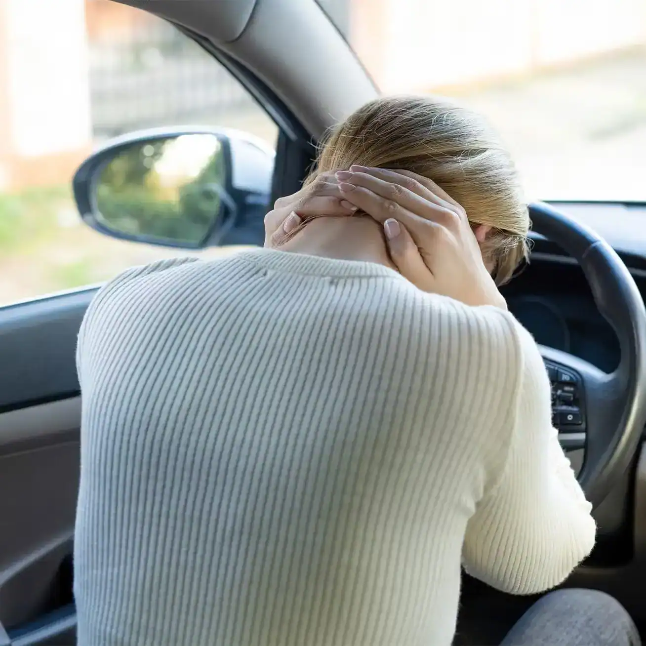 Injured woman holding neck inside car after accident showing whiplash symptoms
