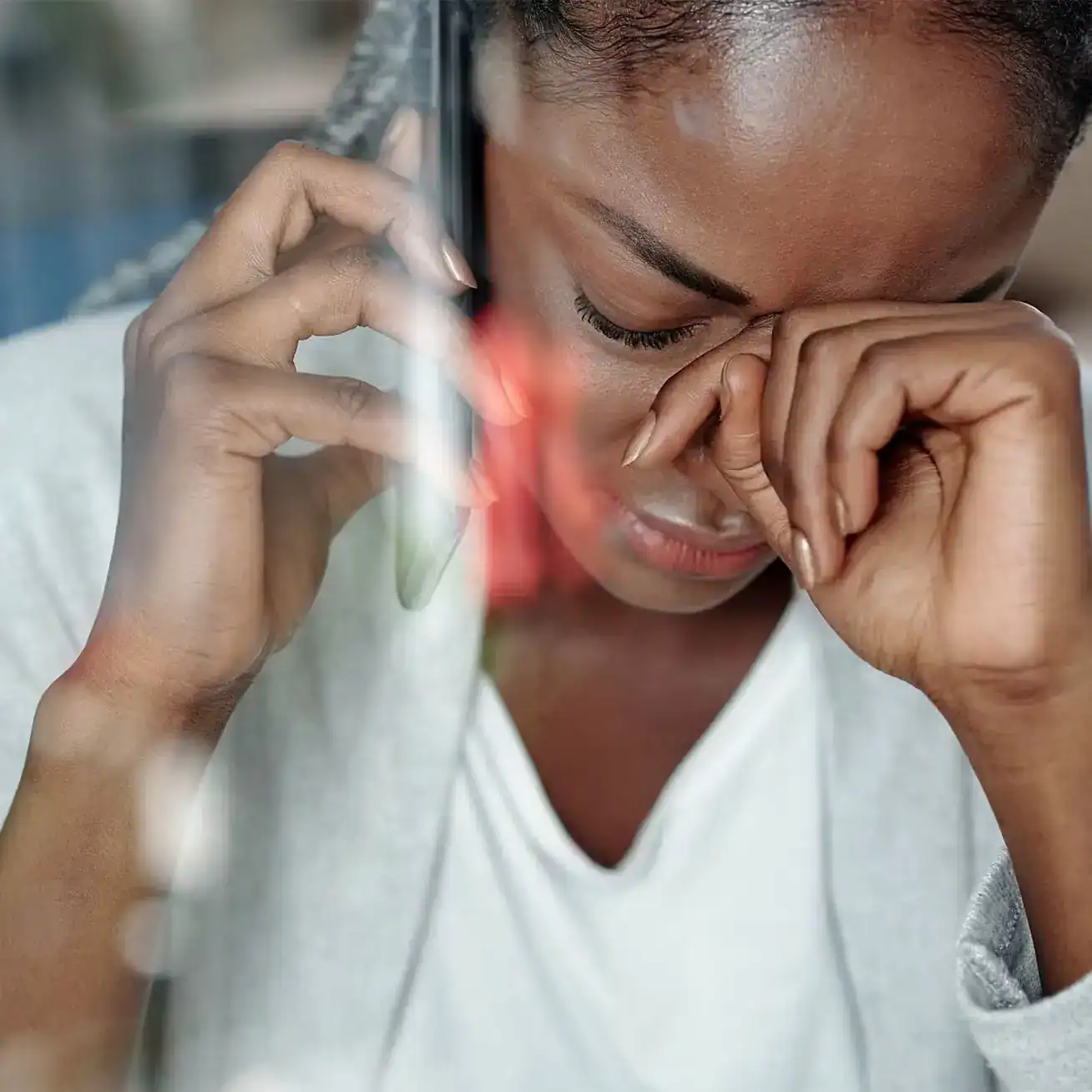 Distressed woman on phone call wiping tears after receiving accident news