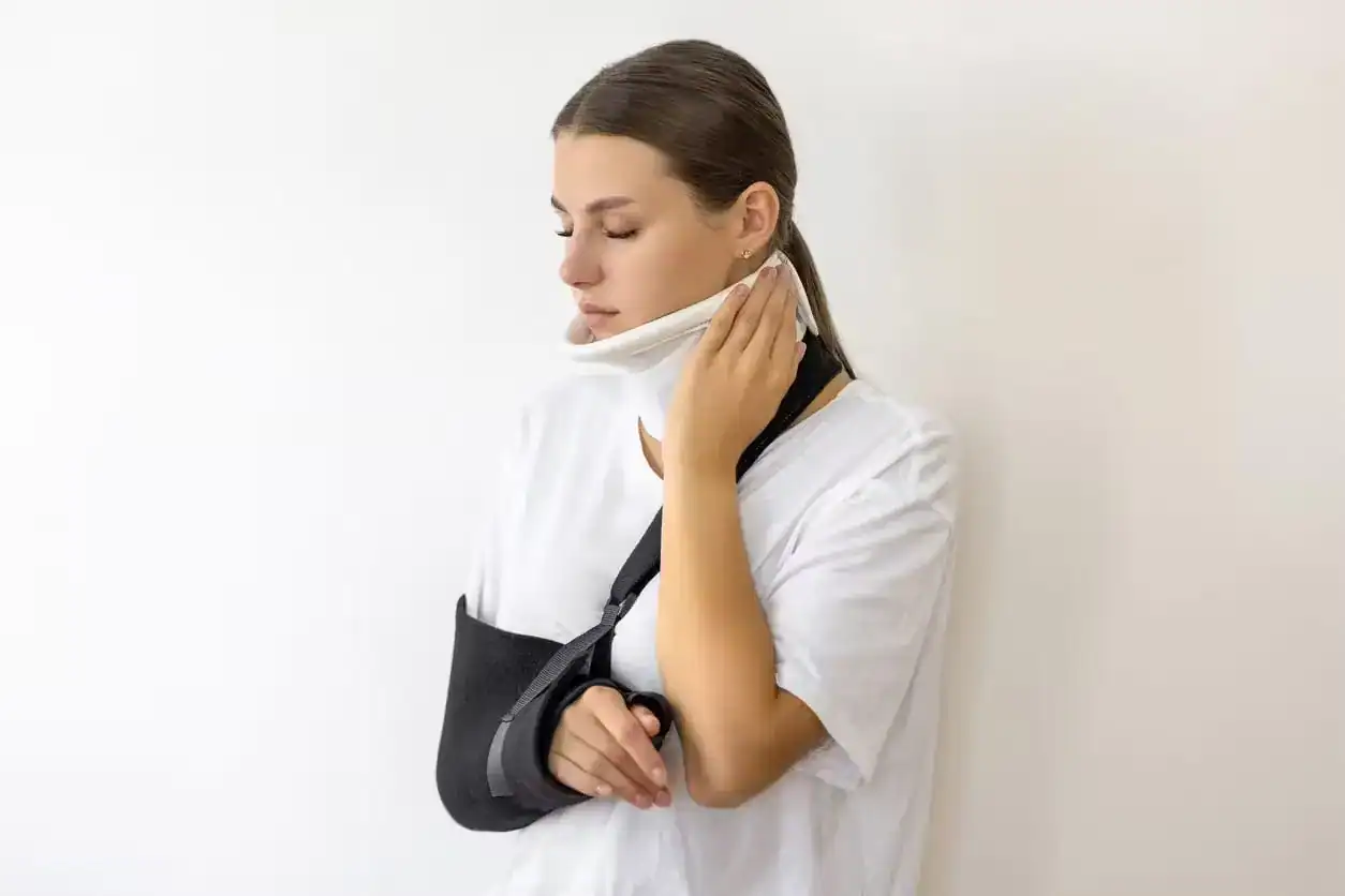Injured woman wearing a neck brace and arm sling after accident, symbolizing personal injury and medical treatment.