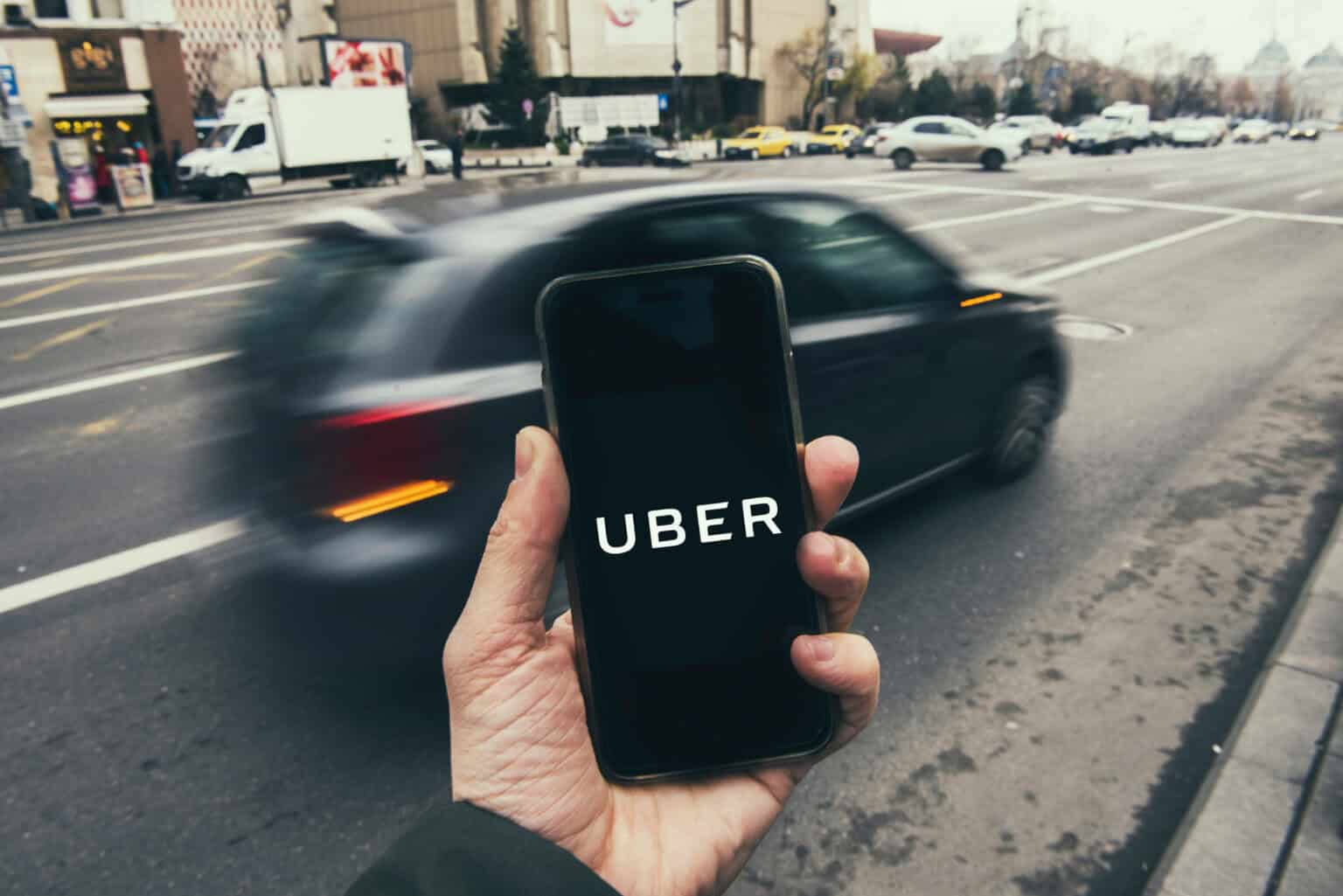 Man Looking At His Phone Showing The Uber App Logo