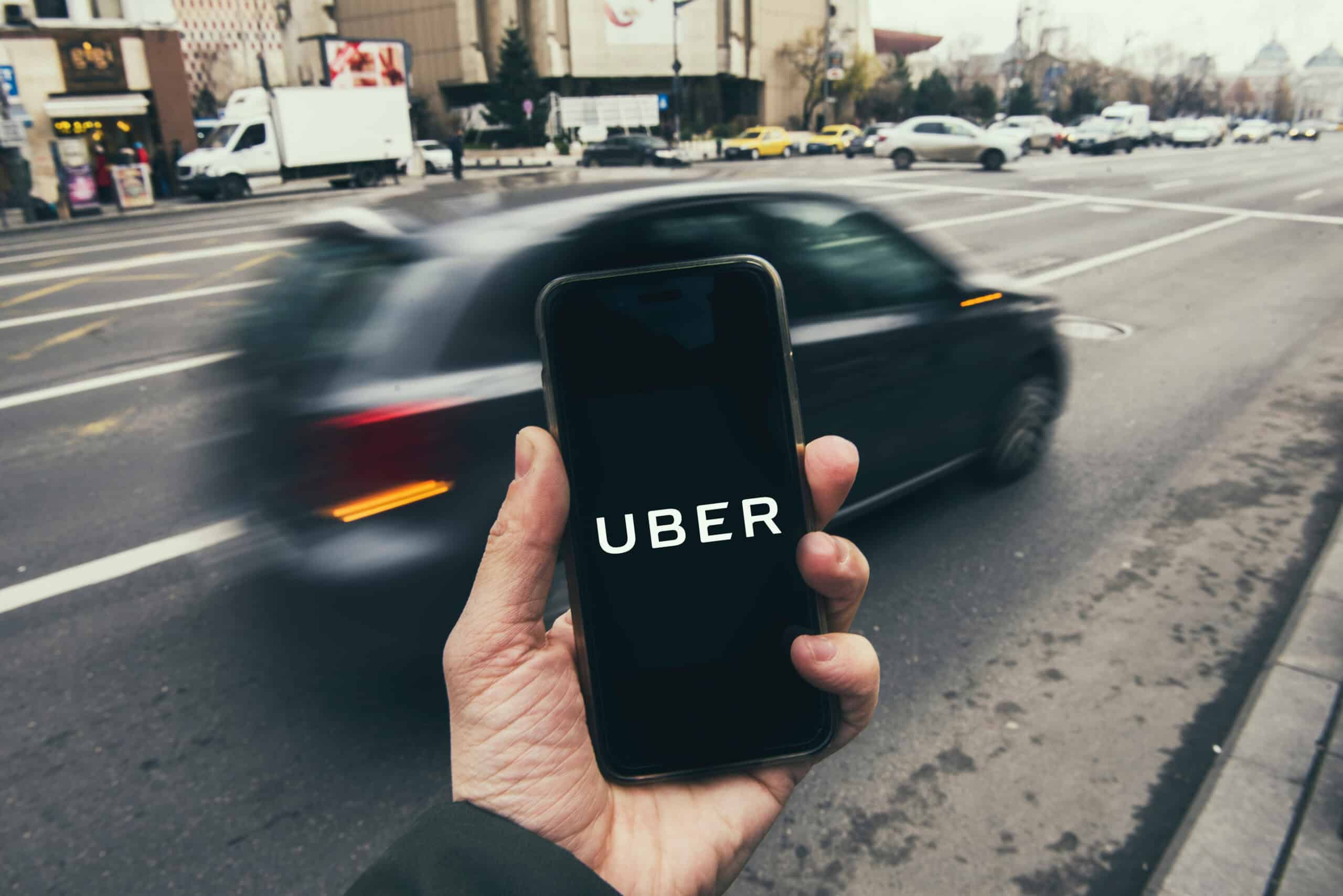 Man Looking At His Phone Showing The Uber App Logo
