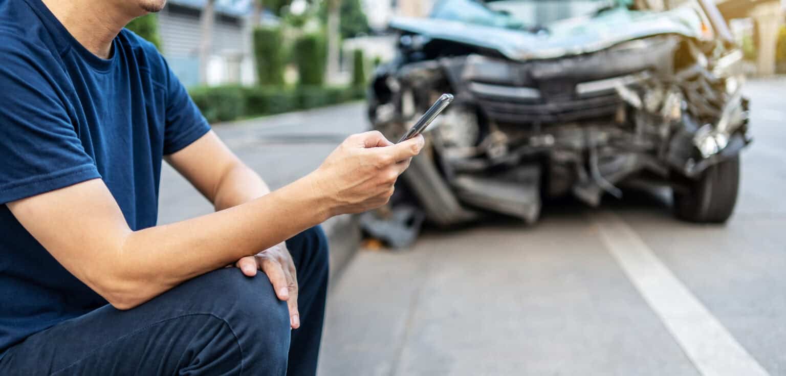 A Man On His Phone Next To A Car Accident