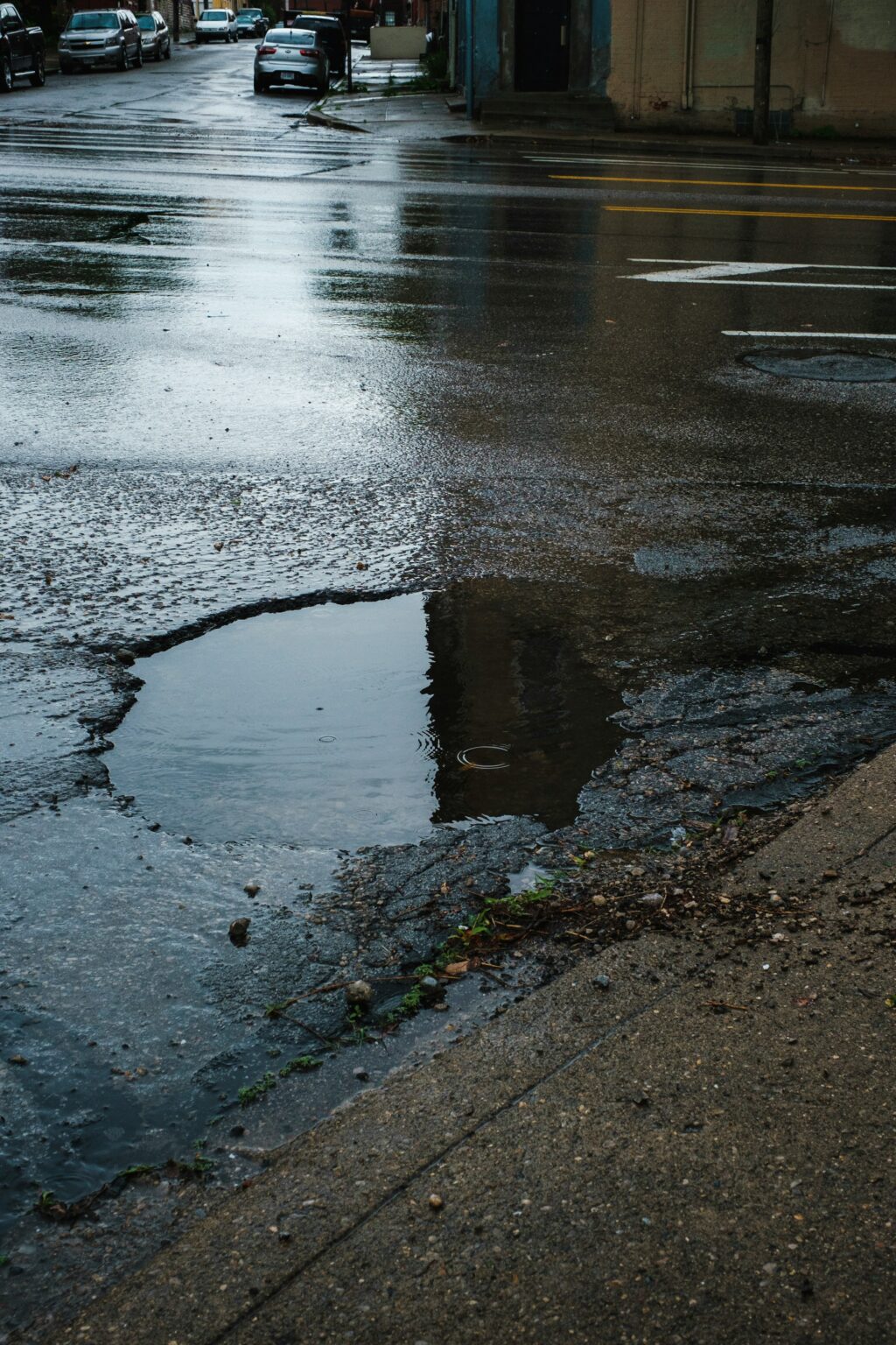 Picture Of A Road With A Pothole Filled With Water
